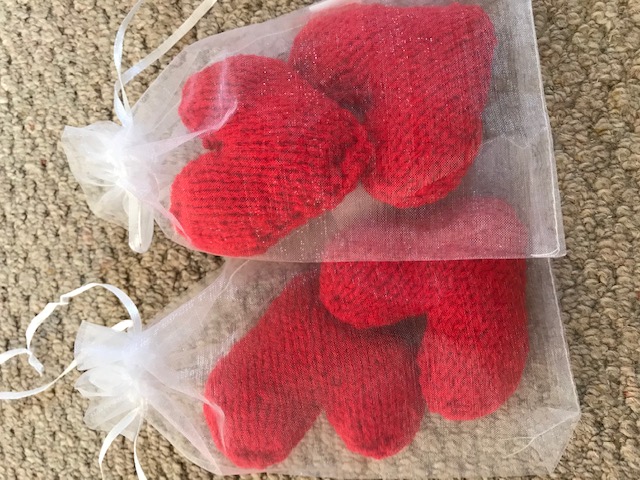 Knitted red hearts in transparent bags