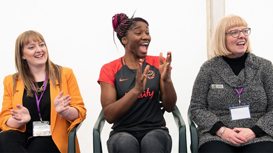 Three women sitting next to each other clapping and laughing