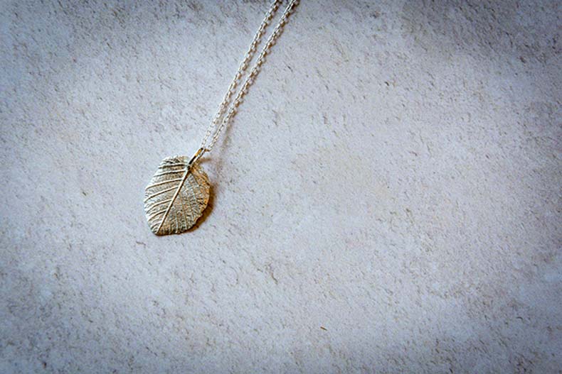 A silver leaf-shaped pendant on a silver chain