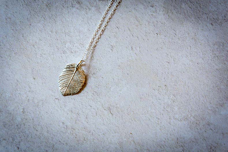 A silver leaf-shaped pendant on a silver chain