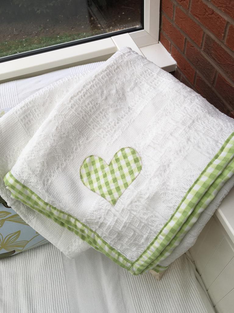 A white blanket with green stitching