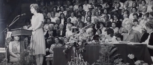 A black and white picture of a WI member speaking at the AM