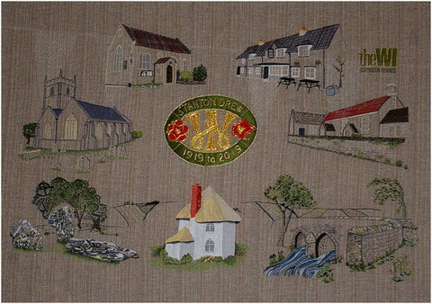 The centenary tapestry, embroidered by our members, depicting local landmarks which is hanging in the Village Hall.