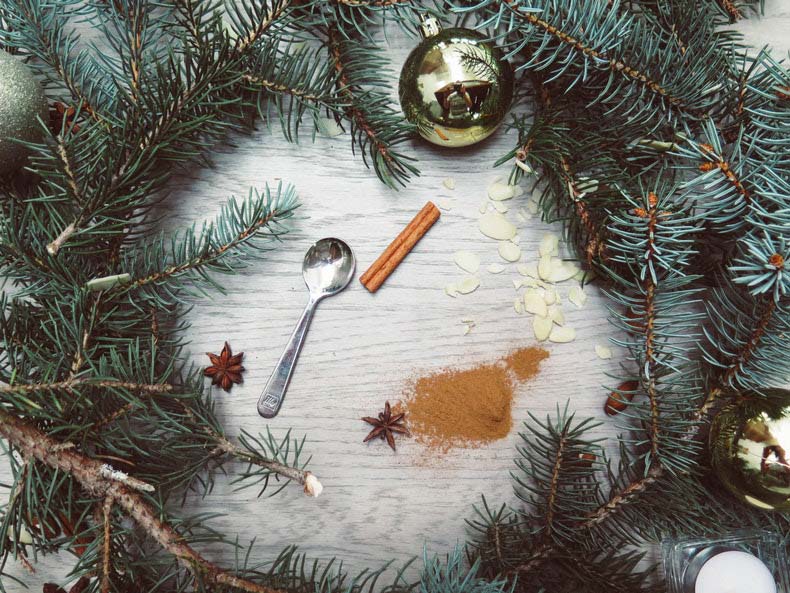 Christmas wreath surrounding a gold bauble, spoon, cinnamon stick and ground cinnamon