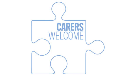 A white/blue piece of a jigsaw puzzle; Carers Welcome written on it