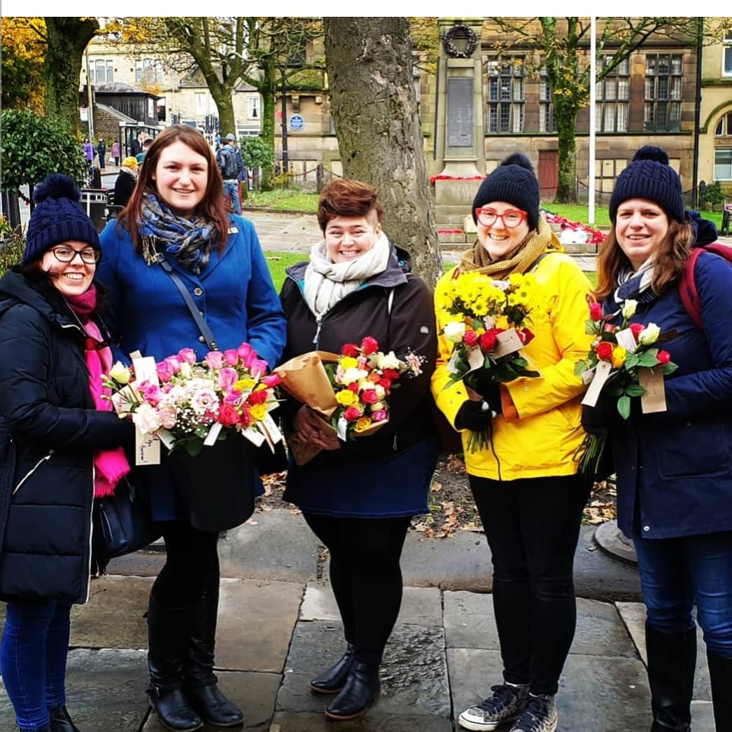 Five women standing outside holding flower bouquets