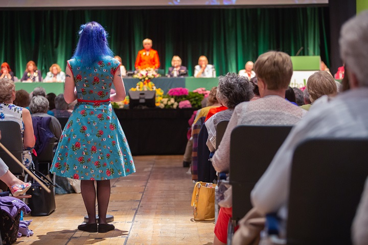 A woman speaking in front of the stage at the Annual Meeting