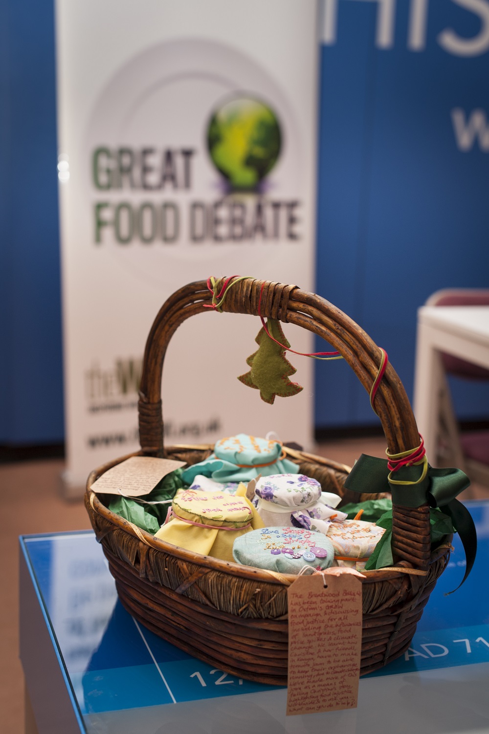 A brown basket with jams and preserves standing on a table