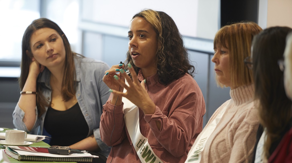 Three women at a desk talking during a panel discussion