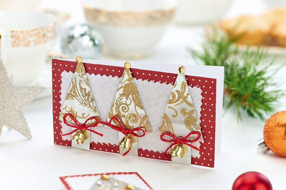 White and red card with small golden Christmas trees placed on a table